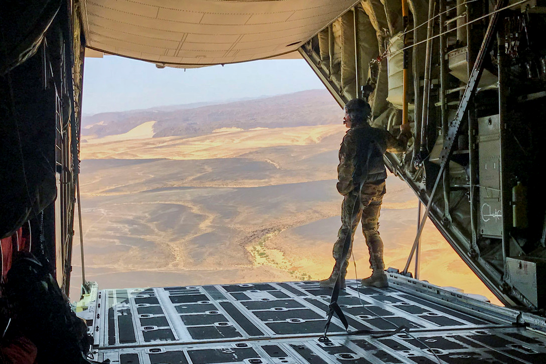 Airman standing on an open cargo door of an airplane