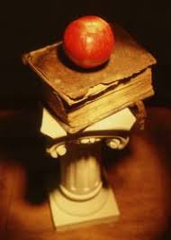 old book sitting on top of a platform.  The book has an apple on top